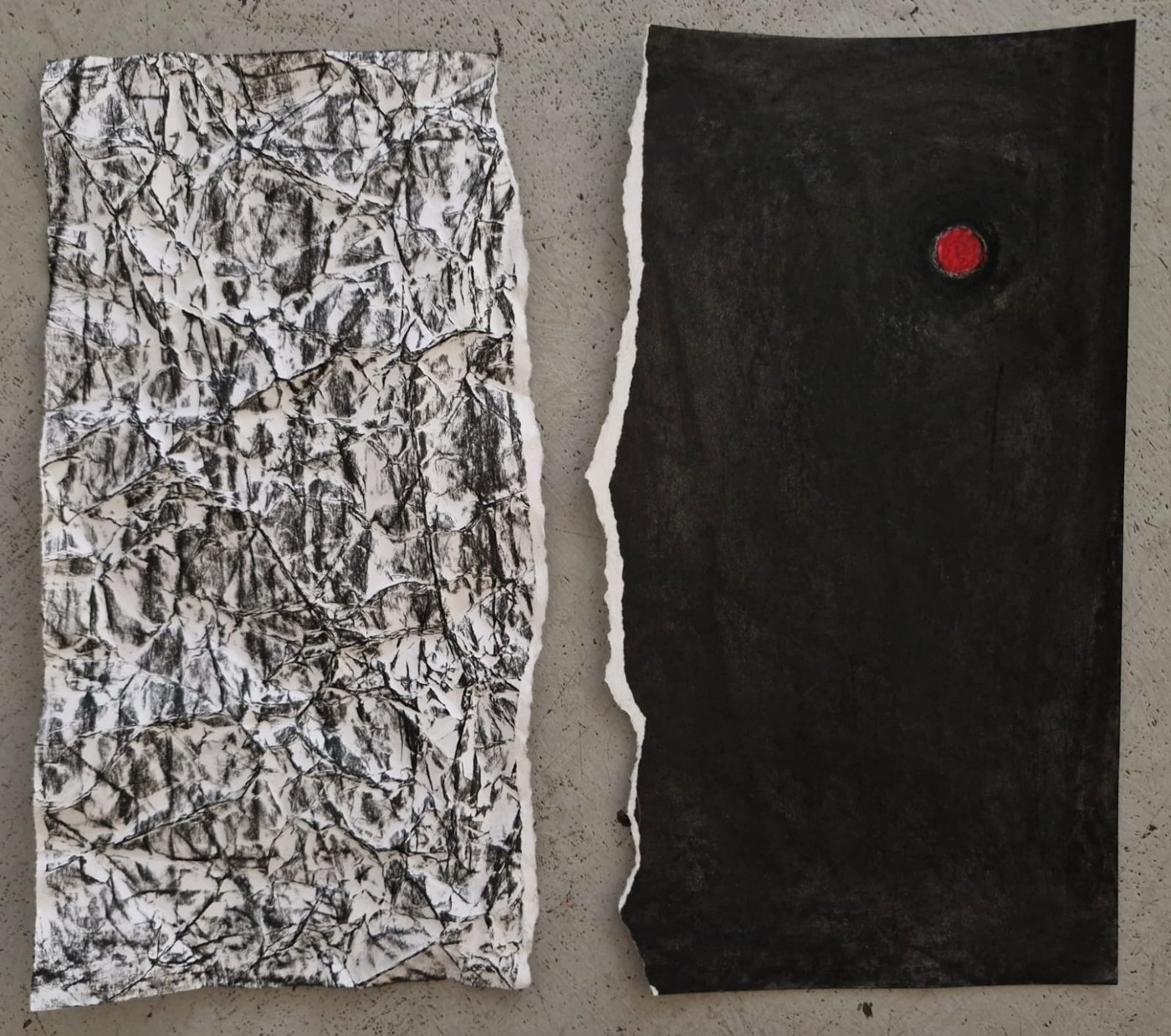 Two torn pieces of paper by Don: on the left, crumpled white paper rubbed with charcoal; on the right, a dark sheet with a single small red circle